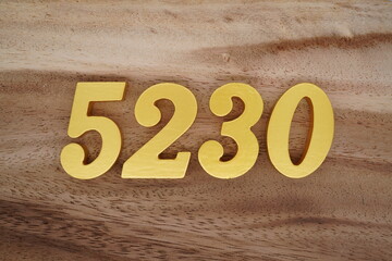 Golden Arabic numerals on a real brown and white wooden floor number 5230