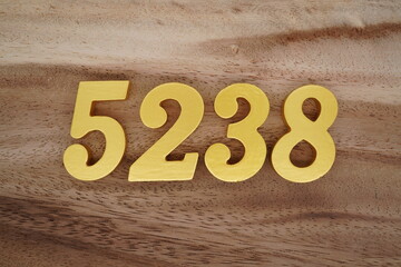 Golden Arabic numerals on a real brown and white wooden floor number 5238