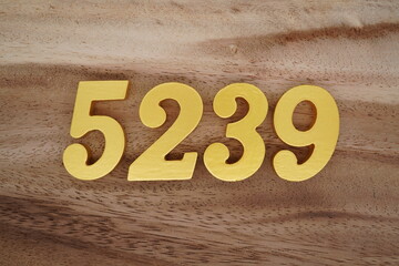 Golden Arabic numerals on a real brown and white wooden floor number 5239