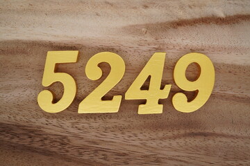Golden Arabic numerals on a real brown and white wooden floor number 5249