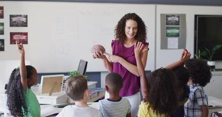 Video of happy caucasian female teacher and diverse school children studying biology in classroom