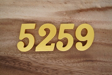 Golden Arabic numerals on a real brown and white wooden floor number 5259
