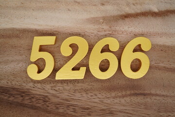 Golden Arabic numerals on a real brown and white wooden floor number 5266
