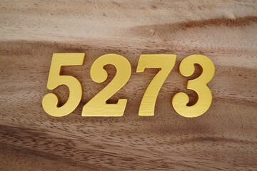 Golden Arabic numerals on a real brown and white wooden floor number 5273