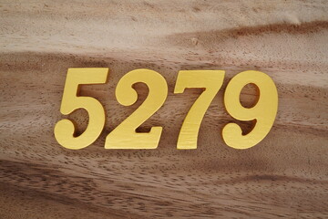 Golden Arabic numerals on a real brown and white wooden floor number 5279