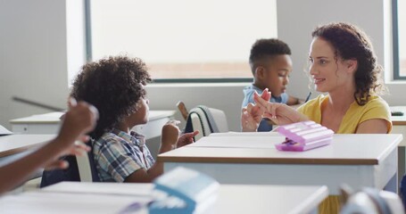Video of happy caucasian female teacher learning math to african american boy