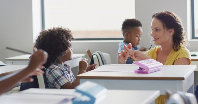 Video of happy caucasian female teacher learning math to african american boy