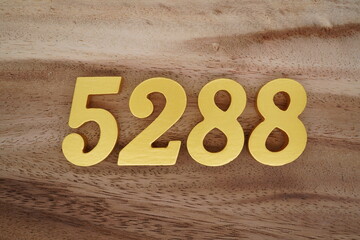 Golden Arabic numerals on a real brown and white wooden floor number 5288