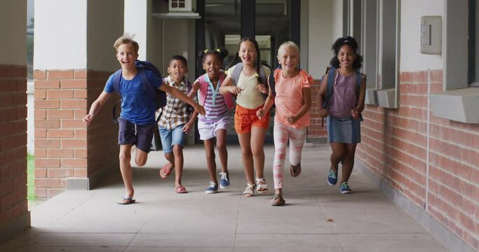 Video of happy diverse pupils running on school corridor