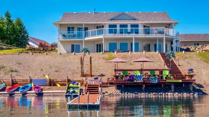 A beautiful contemporary two-story beach house, with large windows, wraparound deck and glass railings, waterfront recreation area, and boat dock. British Columbia, Canada. - obrazy, fototapety, plakaty