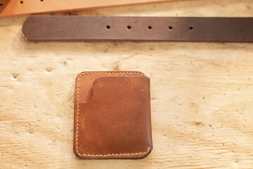 High angle view of leather belt and wallet on wooden table in workshop
