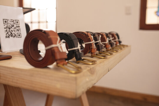 Close-up of various rolled leather belts arranged on wooden table in store