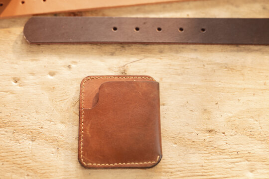 High angle view of leather belt and wallet on wooden table in workshop