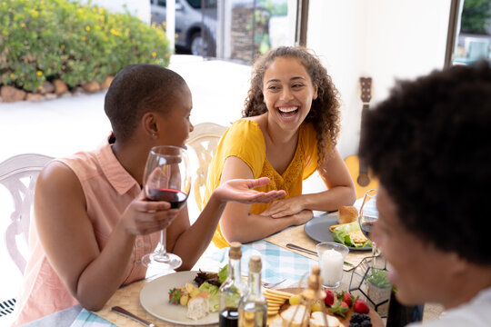 Cheerful young female multiracial friends laughing together while sitting dining table