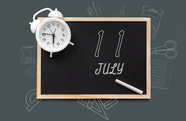july 11. 11th day of month, calendar date. Blackboard with piece of chalk and white alarm clock on green background. Concept of day of year, time planner, summer month