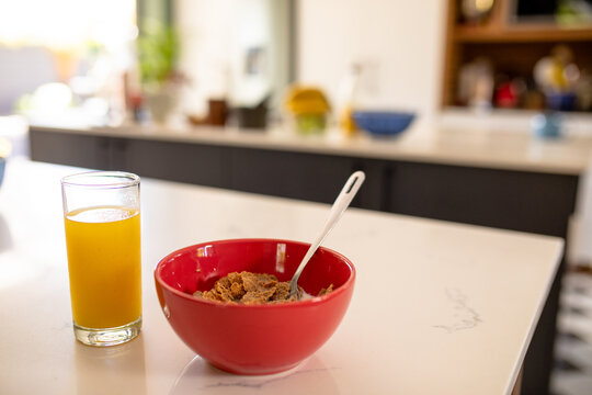 Close-up of orange juice with cornflakes bowl on table in kitchen at home