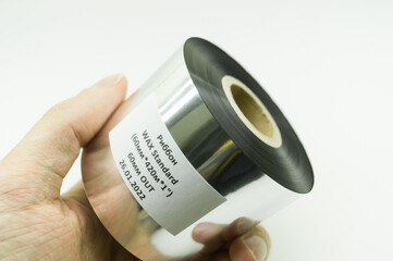 Single thermal transfer ribbon in hand. Wax thermo ribbon on cardboard reel for barcode. Supply...