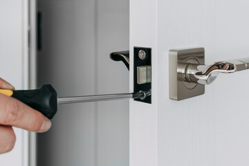A handyman repair the door lock in the room. A locksmith install the new door lock in the room. Selective focus - obrazy, fototapety, plakaty