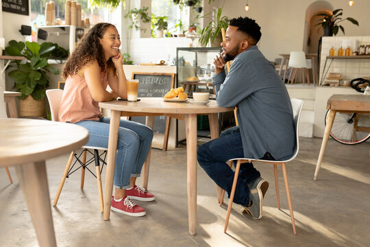 Young african american couple talking while sitting at table in coffee shop