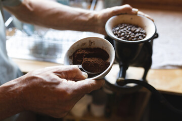 Midsection of caucasian mature man preparing coffee in kitchen at cob house