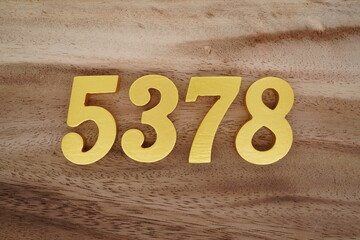 Golden Arabic numerals on a real brown and white wooden floor number 5378