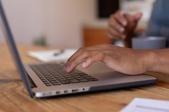 Cropped image of african american young businessman using laptop on table