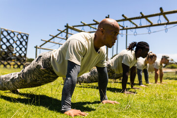 Group of male and female diverse soldiers performing push ups together at boot camp