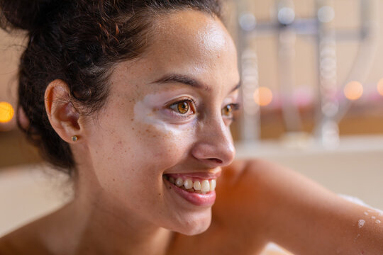 Fototapeta Closeup of smiling beautiful biracial young woman looking away in bathtub at spa