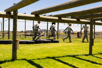 Group of diverse male and female soldiers walking on tires during obstacle course at boot camp