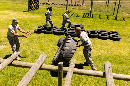 African american male soldier flipping a tire during obstacle course at boot camp - Powered by Adobe