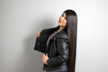Fat latin young adult woman shows off her beautiful very long straight black shiny silky hair wears black fur jacket looks modern, happy and full body positive
