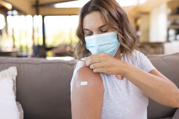 Caucasian pregnant woman wearing a face mask showing her shoulder after getting the vaccine