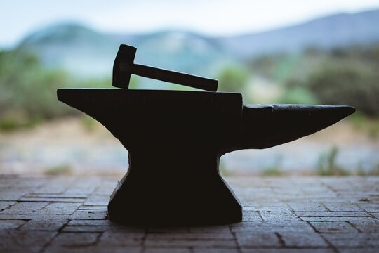 Hammer with wooden handle kept on anvil in metal industry