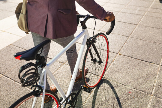 Mid section of businessman with bicycle walking on the street on the go to office