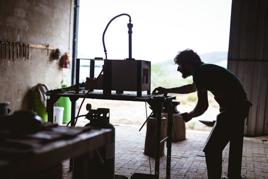Side view of blacksmith working on machinery in manufacturing industry