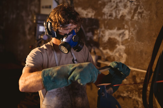 Blacksmith wearing gas mask while working on metal in industry