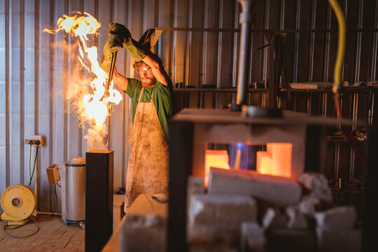 Caucasian blacksmith putting metal in fire while forging in manufacturing industry