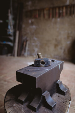 Hammer with wooden handle kept on anvil in manufacturing industry
