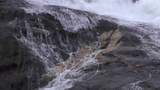 Slow motion waterfall. Water rolls down rock