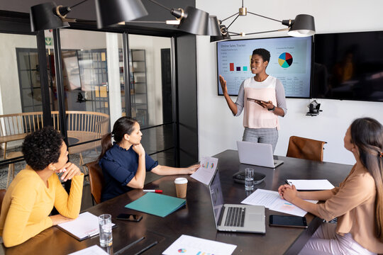 Businesswoman explaining business strategy to multiracial female colleagues in board room