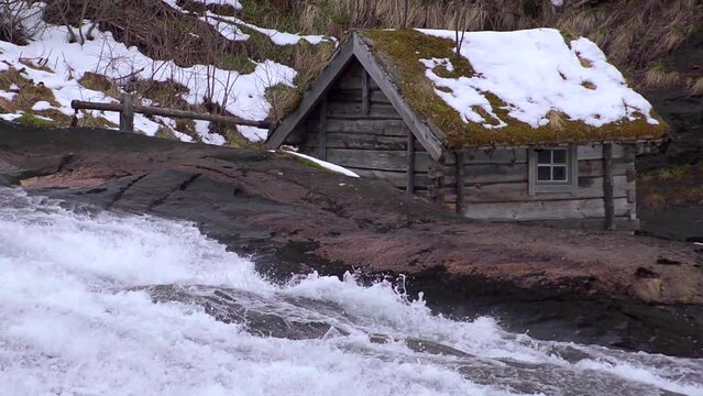 Slow motion waterfall past mill house. Looping