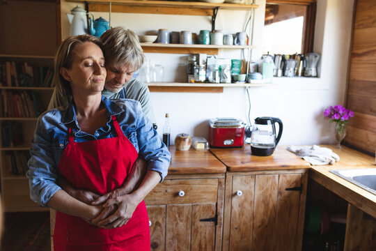 Romantic caucasian mature couple embracing by kitchen counter in home