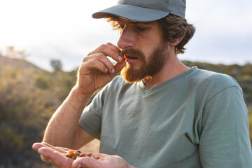 Young bearded caucasian wanderer eating fresh wild berries in forest