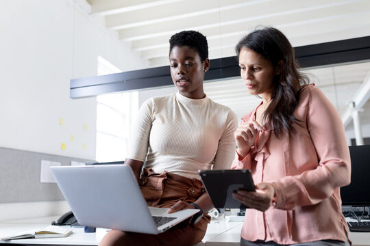 Multiracial creative businesswomen brainstorming over laptop in office