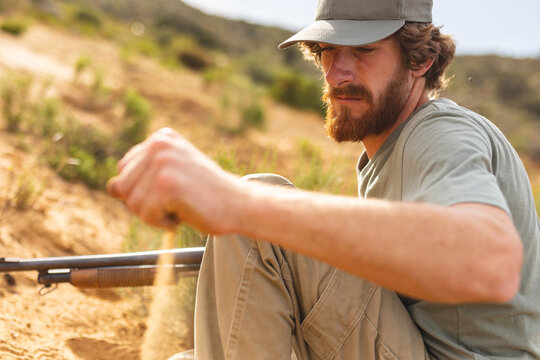 Bearded young male caucasian hunter checking wind while dropping sand from hand