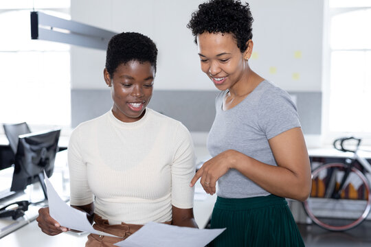 Multiracial businesswomen discussing over documents in creative office