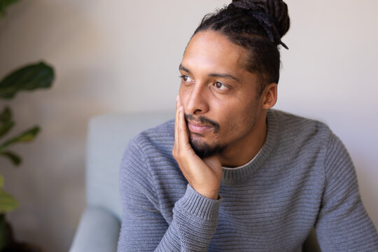 Thoughtful african american young man sitting on a chair at home