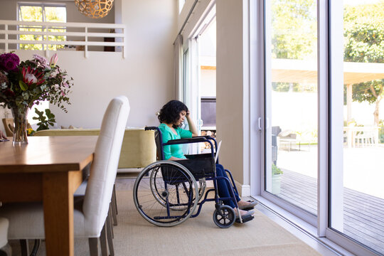 Stressed african american disabled woman on a wheelchair near the window at home
