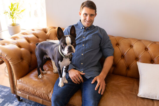 Portrait of caucasian man and dog sitting on the couch at home