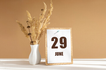 june 29. 29th day of month, calendar date.White vase with dried flowers on desktop in rays of sunlight on white-beige background. Concept of day of year, time planner, summer month